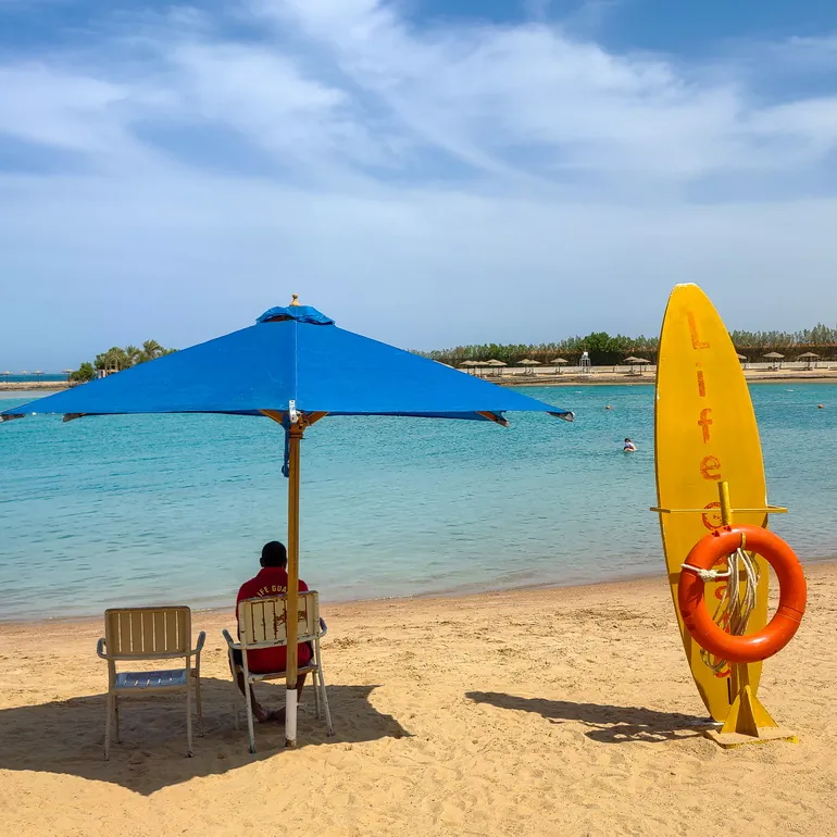 Plavi suncobran i spasilac na hotelskoj plaži
